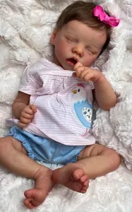 Detailed view of 18-inch sleeping reborn doll on a soft white plush rug with striped outfit