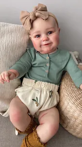 Detail of 60cm reborn doll wearing green top and patterned shorts in cozy basket