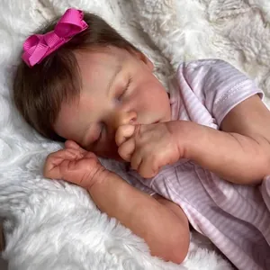 Lifelike 18-inch reborn baby doll with pink bow and striped romper on white plush rug