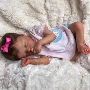 Realistic sleeping 18 inch reborn baby doll with pink bow on soft white plush background