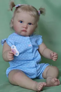 Detailed view of reborn doll Charlotte with blonde hair, pink bow and blue polka dot outfit