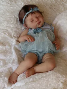 Close-up of 20-inch reborn doll sleeping in blue lace outfit on white plush blanket