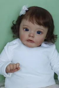 Close-up of 60cm reborn doll with curly brown hair, blue eyes and white lace outfit