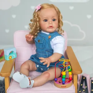 60cm curly blonde reborn toddler doll in denim overalls sitting on a pink sofa