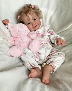 Close-up of 60cm Maddie reborn doll with floral romper and pink teddy bear plush
