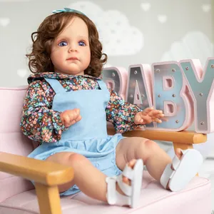 Realistic 60cm reborn toddler doll with curly hair sitting on pink chair in floral outfit