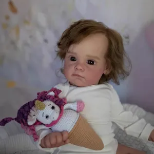 60cm realistic reborn baby doll Maggi in white romper holding a crochet unicorn toy