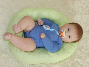 Close-up of baby on green polka dot nursing pillow with lion pacifier clip set