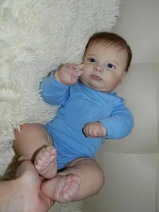 Detailed shot of lifelike 60cm reborn doll feet showing realistic skin texture and blue outfit