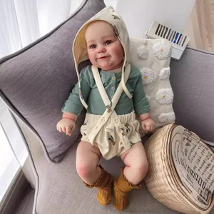 60cm Reborn Toddler Maddie Doll in olive print outfit resting on a cozy grey sofa
