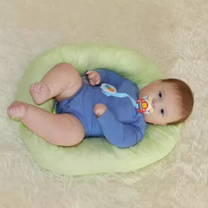 Realistic reborn toddler Joseph doll lying in a green polka dot baby lounger nest