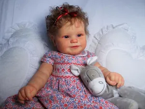 Detail of 60cm Maddie reborn toddler doll with brown curly hair and blue floral dress