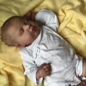 Realistic 19-inch sleeping newborn baby doll wearing a white romper on yellow blanket