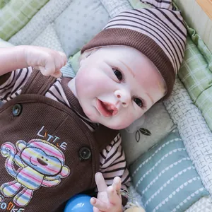 Lifelike 55cm reborn baby doll wearing a brown monkey overall set in a cozy crib