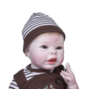 Lifelike 55cm reborn baby doll wearing a striped knit hat and Little embroidered overalls