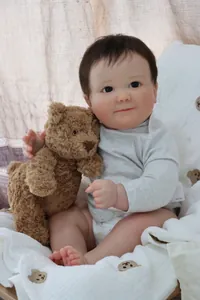 Realistic 60cm reborn baby doll in grey romper with a small plush teddy bear