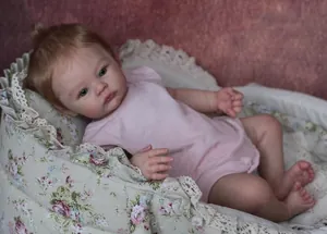 Detailed view of 18 inch Meadow reborn doll with realistic skin and pink romper in a bassinet