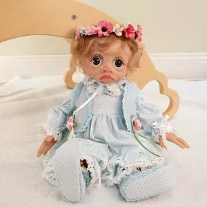 Close-up of 17 inch elf baby doll with purple eyes and blue lace dress on plush rug