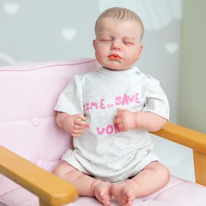 Poupée Reborn réaliste de 19 pouces endormie en body gris assise sur un fauteuil rose