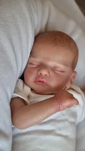 Dettaglio di una bambola reborn che dorme con pelle realistica e body in cotone bianco