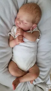 Dettaglio di una bambola reborn realistica che dorme con pelle testurizzata e tutina bianca