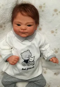 Detail of 49cm reborn baby doll wearing a best friends outfit on a white plush rug