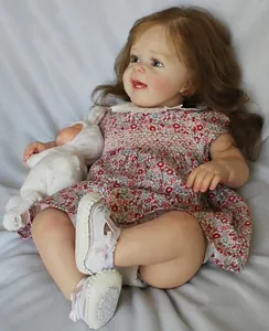 Close-up of lifelike Yannik reborn doll with curly hair and plush bunny accessory