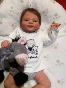 Detailed view of 49cm reborn baby doll with brown hair, bear top, and grey donkey toy