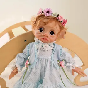 Detail of 17 inch elf doll with brown curls and blue polka dot dress in wooden cradle