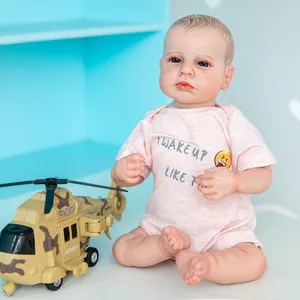 Poupée bébé reborn réaliste de 48 cm en barboteuse rose à côté d'un hélicoptère jouet
