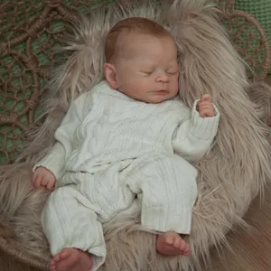 Sleeping reborn baby doll 46cm in white knit romper within a woven basket