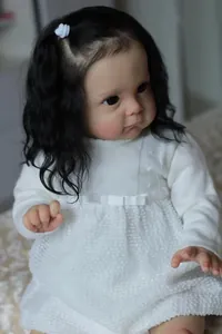 Dettaglio di una bambola reborn realistica da 60 cm con capelli ricci e abito in maglia