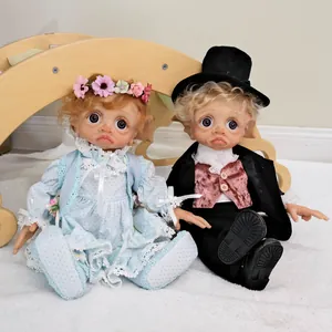 Pair of 17-inch realistic elf reborn dolls sitting on a soft white plush rug