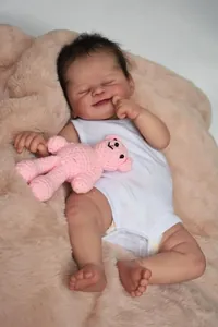 Detail of 19 inch reborn baby doll Alisha with realistic skin and pink crochet bear