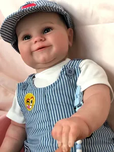 Detail of reborn baby doll in blue striped overalls and cap on a soft pink background