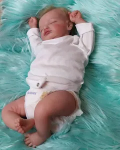 Gros plan d'une poupée Reborn endormie avec des plis cutanés réalistes sur peluche menthe
