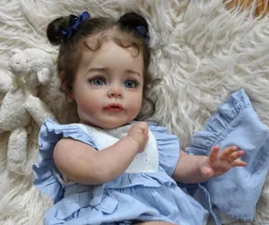 Detail of 60cm reborn baby doll with brown curls and blue bow on white faux fur carpet