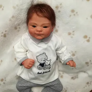 Lifelike 49cm reborn baby doll with brown hair wearing bear embroidery outfit on plush rug