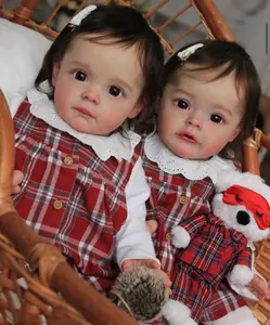 Gros plan de poupées Reborn réalistes en robes à carreaux sur une chaise en osier