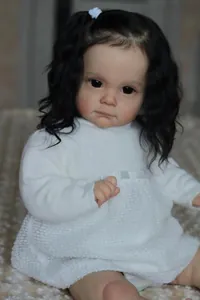 Dettaglio della bambola reborn da 60cm con capelli neri ricci e abito bianco in maglia