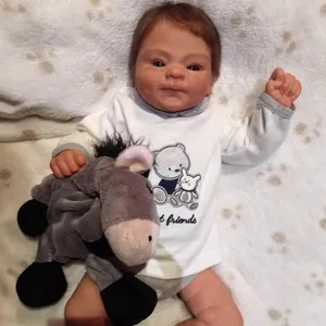 Realistic 49cm reborn baby doll in white romper holding a grey plush donkey toy