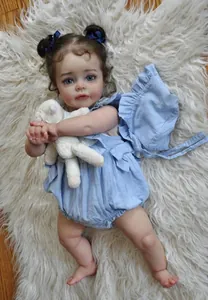 Detailed close-up of 60cm reborn baby doll with blue romper and white lamb plush toy