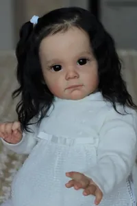 Dettaglio bambola reborn 60cm con capelli ricci neri e vestito in maglia bianca