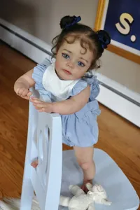 Detail of 60cm lifelike reborn baby doll in blue romper on a wooden chair with bunny
