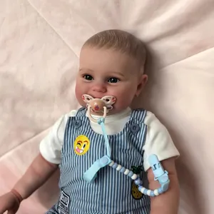 Realistic 60cm reborn baby boy doll with blue eyes in striped blue overalls and pacifier