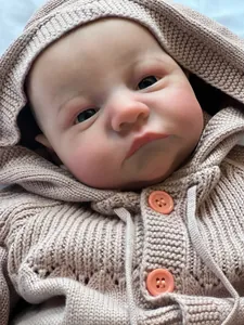 Close-up of lifelike reborn baby doll face with 3D skin texture and pink knit sweater