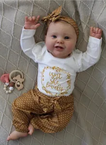 Realistic 60cm reborn doll in white bodysuit and yellow polka dot trousers set