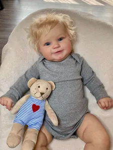Macro detail of Maddie reborn doll with blonde curls, blue eyes and small teddy bear
