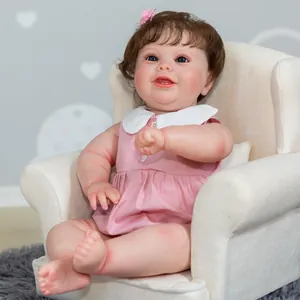 Realistic 50cm reborn baby girl doll with brown hair and pink dress sitting on a sofa