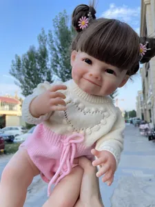 Gros plan d'une poupée reborn réaliste avec fossettes, cheveux bruns et barrettes